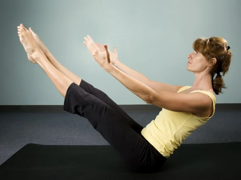 A woman demonstrating a balance yoga pose on a mat, promoting fall prevention through flexibility exercises.