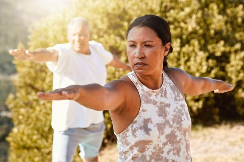 An older couple engaged in outdoor in yoga, promoting healthy aging and physical well-being.